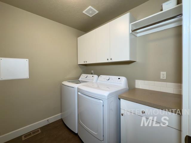 laundry room with dark wood-type flooring, cabinets, and washer and clothes dryer