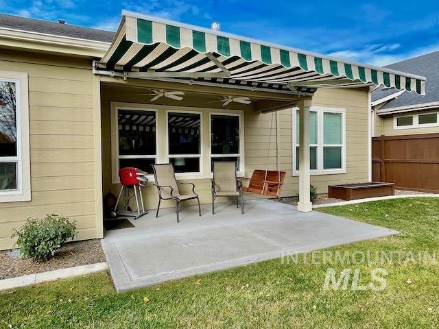 back of property with ceiling fan, a patio area, and a lawn