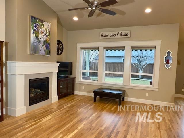 living area with lofted ceiling, hardwood / wood-style floors, and ceiling fan