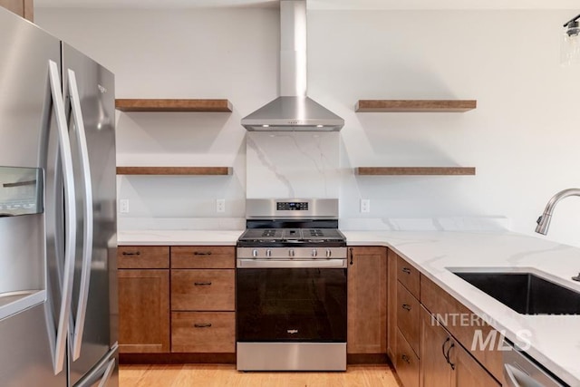 kitchen with open shelves, appliances with stainless steel finishes, brown cabinetry, and wall chimney range hood