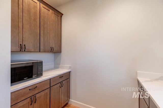 kitchen with baseboards, black microwave, and brown cabinets