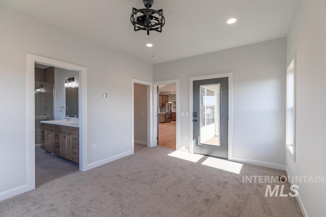 unfurnished bedroom with recessed lighting, light colored carpet, freestanding refrigerator, connected bathroom, and baseboards