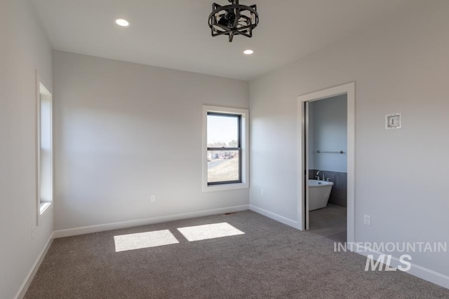 unfurnished bedroom featuring baseboards, ensuite bathroom, carpet flooring, and recessed lighting