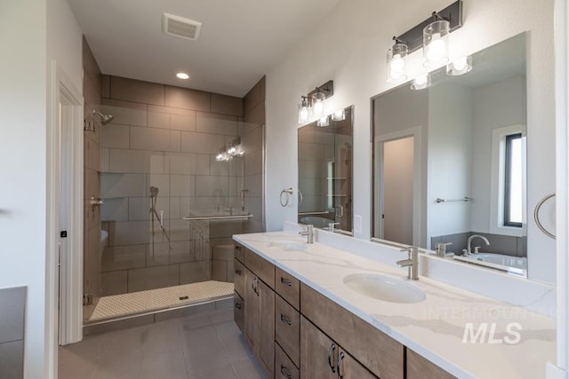 bathroom featuring double vanity, a shower stall, visible vents, and a sink