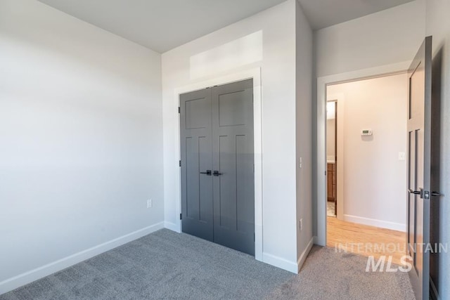 unfurnished bedroom featuring carpet floors, baseboards, and a closet