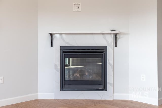 room details with a premium fireplace, baseboards, and wood finished floors