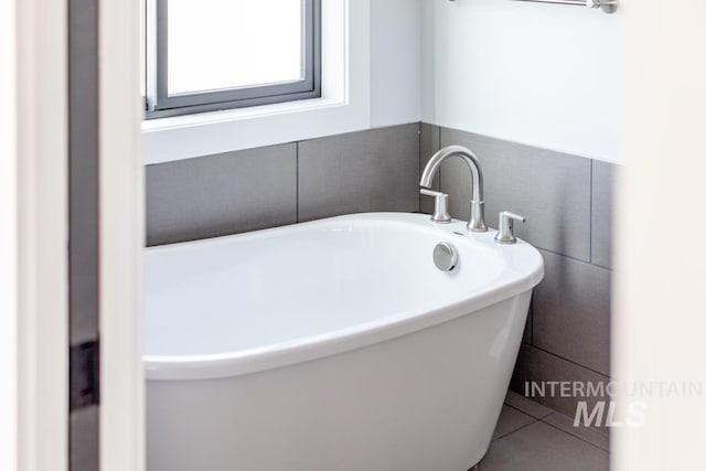 bathroom with a soaking tub and tile patterned flooring