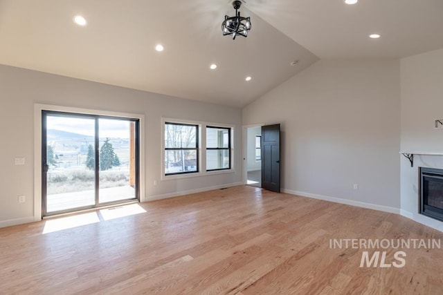 unfurnished living room featuring a glass covered fireplace, light wood-style flooring, baseboards, and recessed lighting