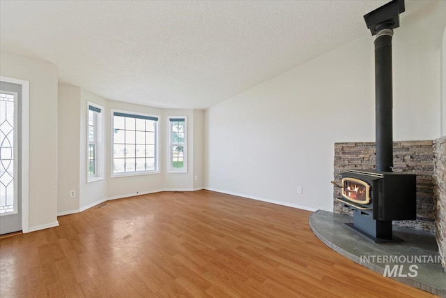 7267 Bowmont Rd, Nampa, ID 83686 - unfurnished living room with a wood stove, light wood-style flooring, and baseboards