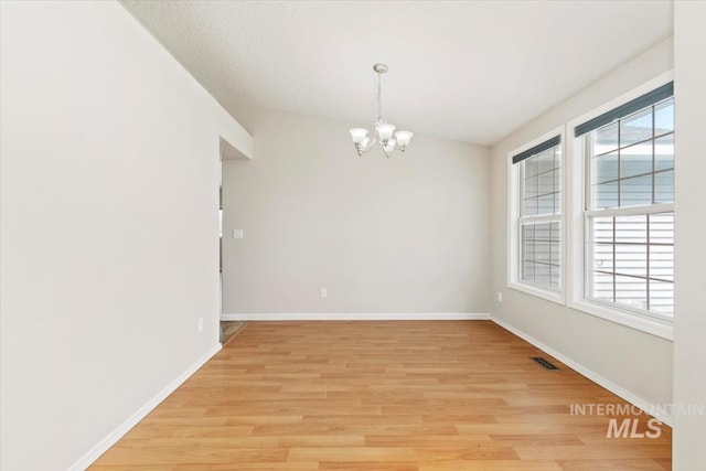 7267 Bowmont Rd, Nampa, ID 83686 - spare room featuring a chandelier, healthy amount of natural light, light wood-type flooring, and baseboards