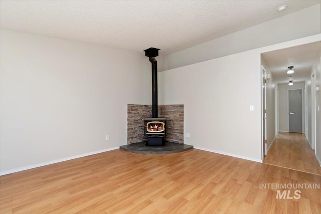 7267 Bowmont Rd, Nampa, ID 83686 - unfurnished living room featuring wood finished floors, baseboards, a wood stove, and a textured ceiling