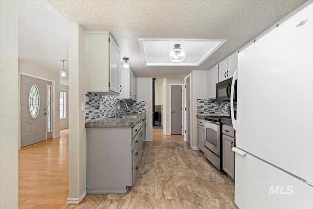 7267 Bowmont Rd, Nampa, ID 83686 - kitchen featuring freestanding refrigerator, stainless steel electric stove, black microwave, a tray ceiling, and backsplash
