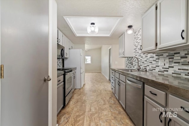 7267 Bowmont Rd, Nampa, ID 83686 - kitchen featuring stainless steel appliances, a tray ceiling, a sink, tasteful backsplash, and white cabinets