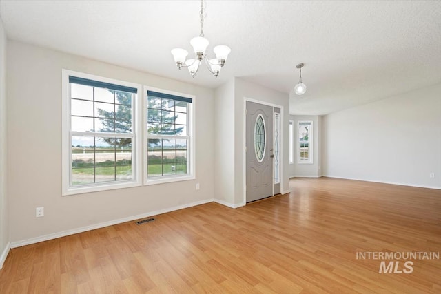 7267 Bowmont Rd, Nampa, ID 83686 - empty room with a chandelier, plenty of natural light, light wood-type flooring, and baseboards
