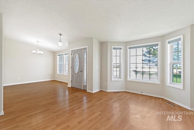 7267 Bowmont Rd, Nampa, ID 83686 - foyer entrance featuring light wood finished floors, a chandelier, plenty of natural light, a textured ceiling, and baseboards