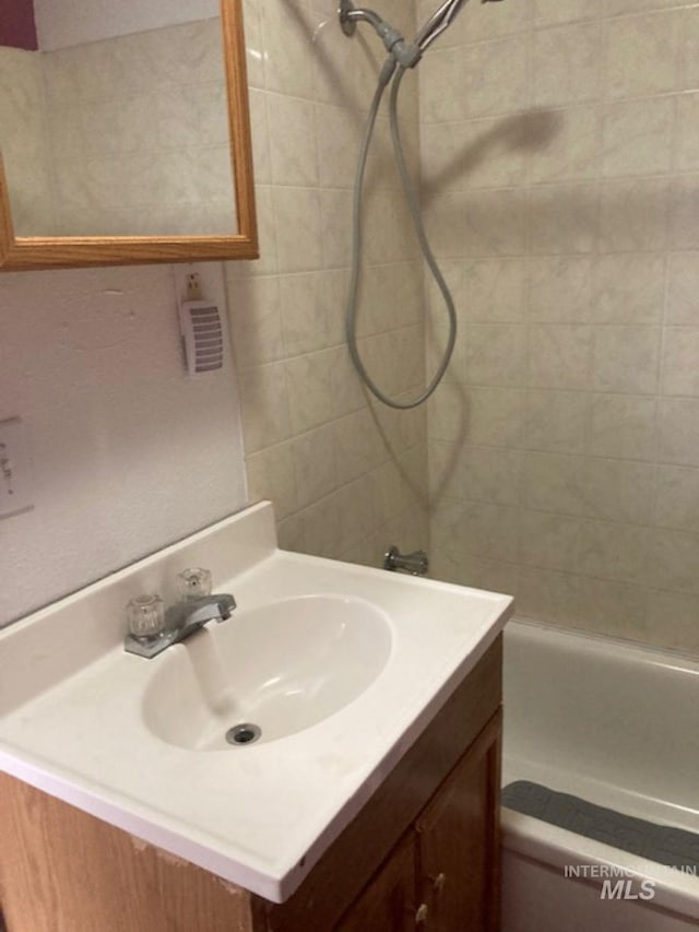 bathroom with tiled shower / bath and vanity