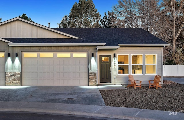 view of front of property with roof with shingles, concrete driveway, fence, a garage, and stone siding