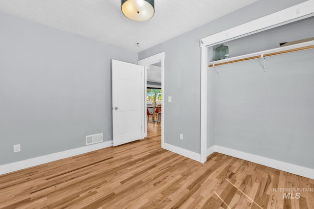unfurnished bedroom with wood finished floors, baseboards, and a closet