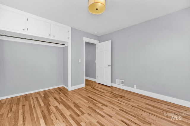 unfurnished bedroom with light wood-style flooring, baseboards, and a closet