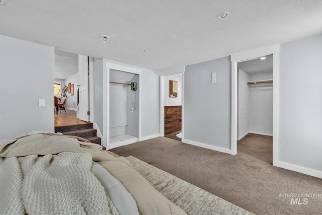carpeted bedroom featuring a walk in closet, baseboards, a textured ceiling, and a closet
