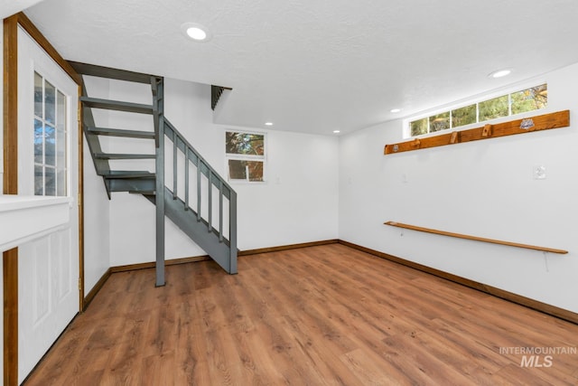 basement featuring stairway, baseboards, healthy amount of natural light, wood finished floors, and recessed lighting