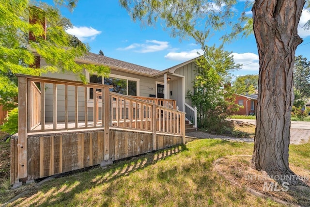 rear view of house with a deck and a yard