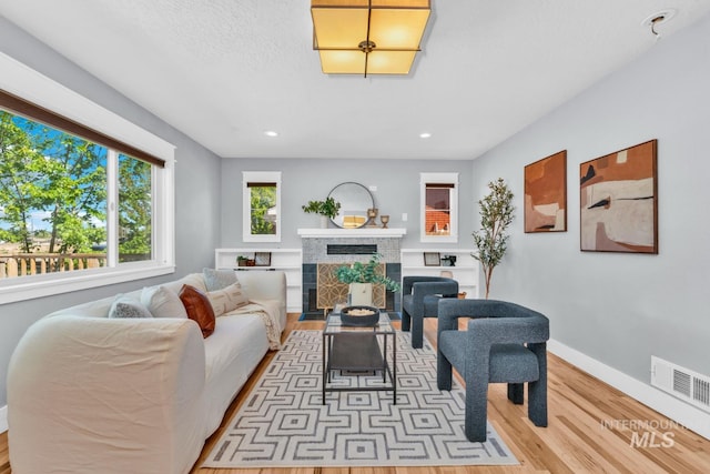 living room featuring light wood finished floors, baseboards, a fireplace, and recessed lighting