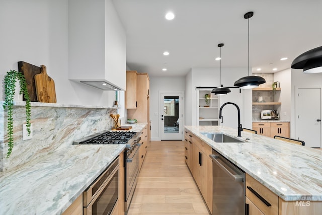 kitchen featuring a kitchen island with sink, appliances with stainless steel finishes, hanging light fixtures, light stone countertops, and sink