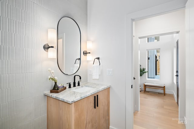 bathroom with tile walls, vanity, and wood finished floors