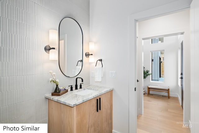 bathroom featuring wood finished floors, tile walls, and vanity