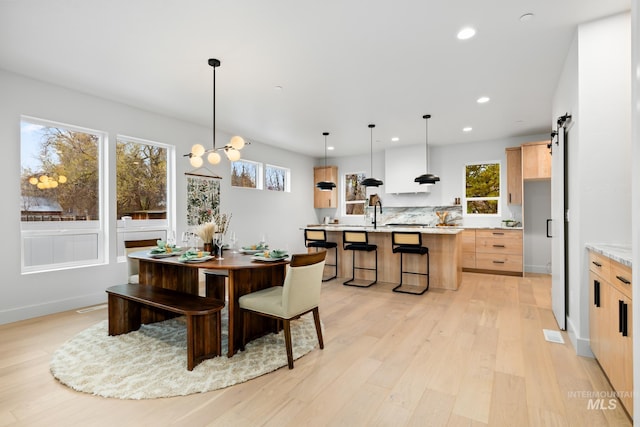 dining room featuring recessed lighting, light wood-style flooring, a barn door, a chandelier, and baseboards