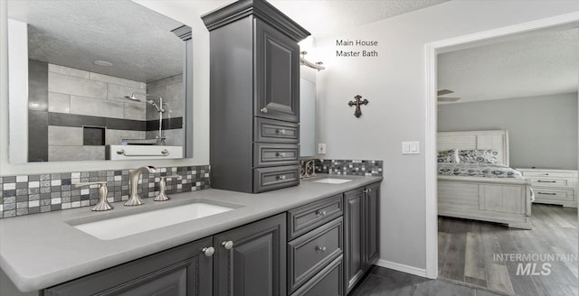 bathroom featuring a textured ceiling, connected bathroom, tasteful backsplash, tiled shower, and double vanity