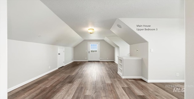 additional living space featuring wood finished floors, baseboards, and vaulted ceiling