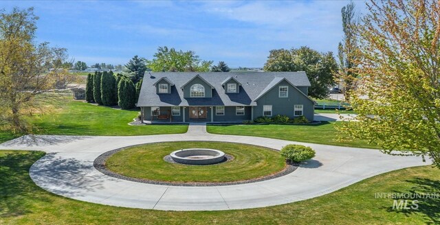 view of front of home with curved driveway, a front yard, and a fire pit