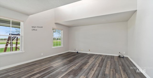 spare room with dark wood-style flooring and baseboards