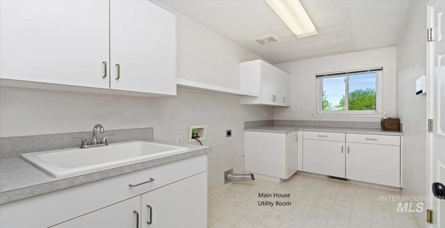 laundry area with electric dryer hookup, cabinet space, hookup for a washing machine, and light flooring