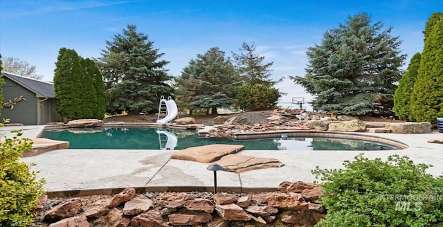 outdoor pool featuring a water slide and a patio area