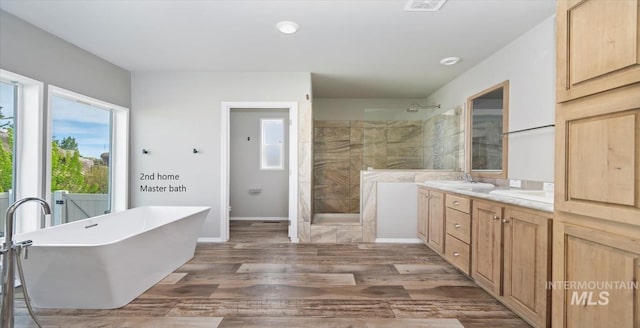 full bath with walk in shower, wood finished floors, a freestanding bath, vanity, and baseboards