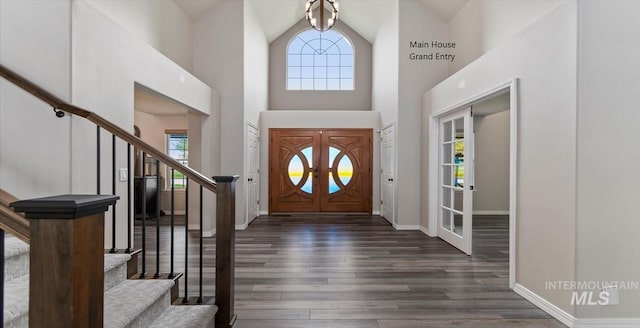 foyer featuring stairs, dark wood-style floors, baseboards, and a towering ceiling