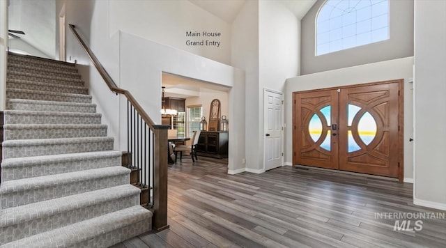 foyer entrance featuring stairs, wood finished floors, baseboards, and a towering ceiling