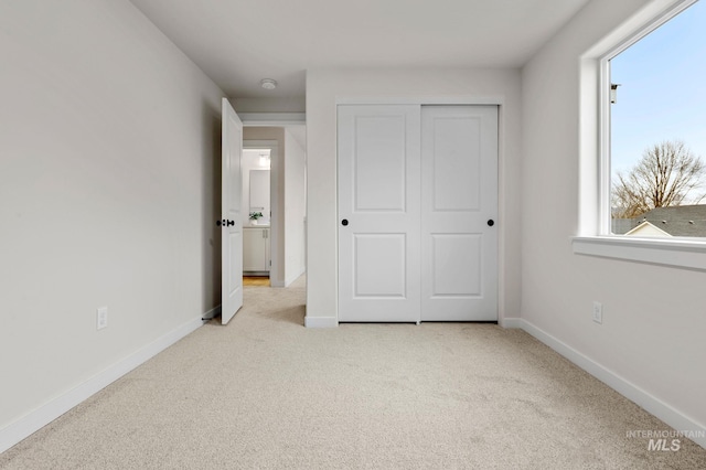 unfurnished bedroom featuring light colored carpet and a closet