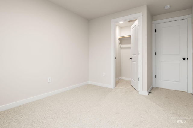 unfurnished bedroom with light carpet, a closet, and a spacious closet