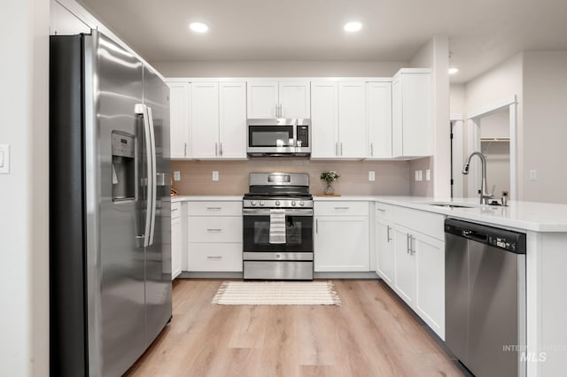 kitchen with sink, tasteful backsplash, light hardwood / wood-style floors, white cabinetry, and stainless steel appliances