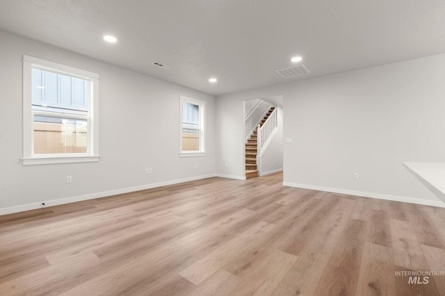 unfurnished living room featuring a wealth of natural light and light hardwood / wood-style flooring