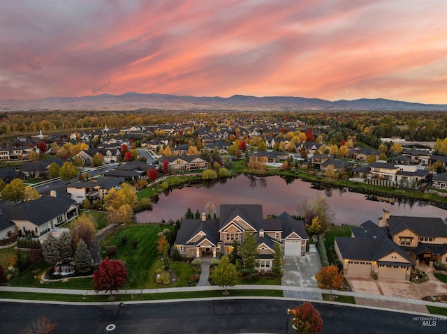 aerial view at dusk featuring a water and mountain view