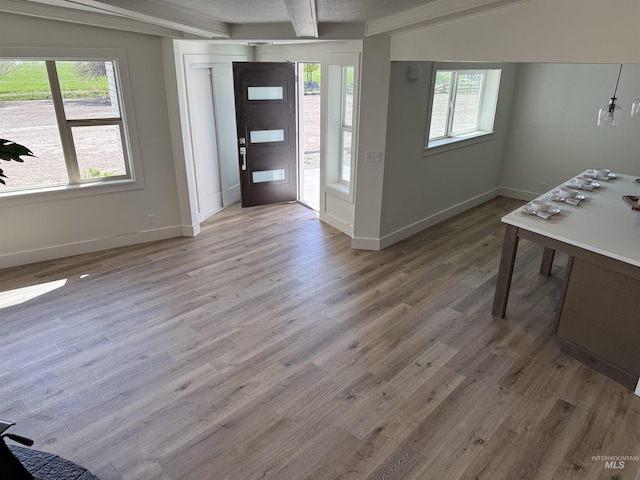 foyer with baseboards, beam ceiling, and wood finished floors