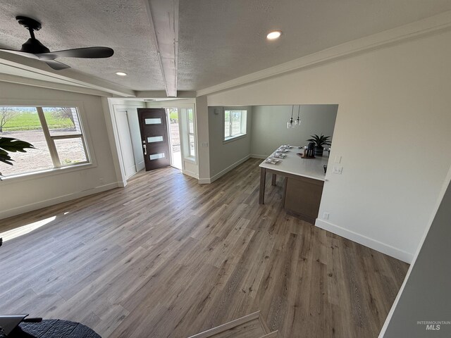 interior space with baseboards, a textured ceiling, ceiling fan, and wood finished floors