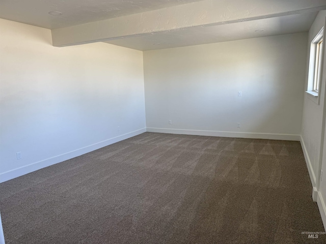 empty room featuring baseboards and dark carpet