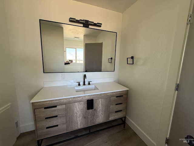 bathroom featuring baseboards, wood finished floors, and vanity