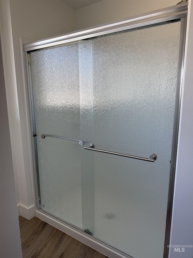 bathroom with a shower stall and wood finished floors